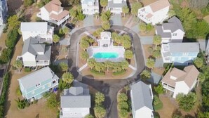An aerial view of a residential area with houses, a central swimming pool, and a road. - Charming 3-BR house, ocean views, community saltwater pool and fishing dock.  (North Topsail Beach)