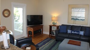 A living room with a television, a sofa, a coffee table, and a fireplace. - Charming 3-BR house, ocean views, community saltwater pool and fishing dock.  (North Topsail Beach)
