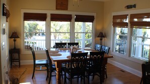 A dining area with a wooden table, black chairs, and a ceiling fan. - Charming 3-BR house, ocean views, community saltwater pool and fishing dock.  (North Topsail Beach)