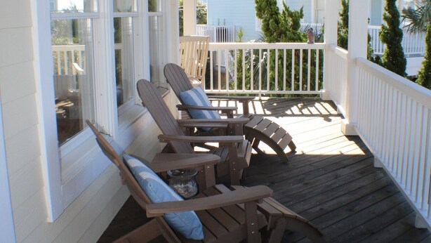 A covered porch with wooden rocking chairs and a table. - Charming 3-BR house, ocean views, community saltwater pool and fishing dock.  (North Topsail Beach)