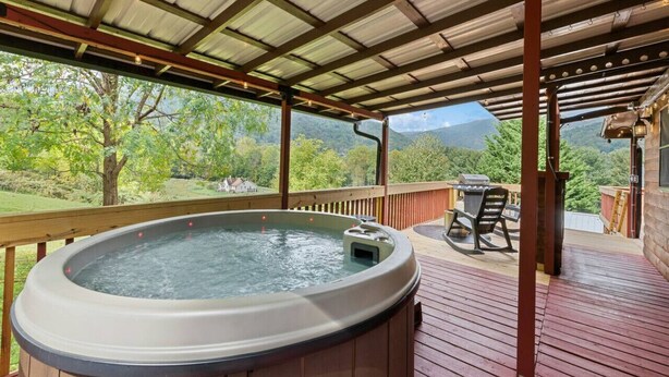 Un jacuzzi en una terraza de madera con vistas a un paisaje montañoso.
