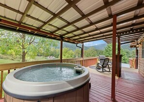 Ein Whirlpool auf einer Holzterrasse mit Blick auf eine Berglandschaft.