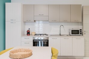 Eine moderne Küche mit weißen Schränken, einem Edelstahlbackofen, einer Mikrowelle und einem Spülbecken.