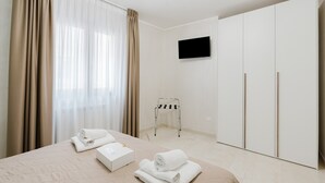 Ein Hotelzimmer mit Bett, Fernseher, Kleiderschrank und einem kleinen Tisch mit Handtüchern.