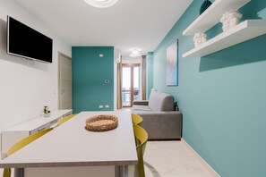 Ein modernes Wohnzimmer mit Fernseher, Esstisch und Sofa.