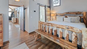 Ein Schlafzimmer mit einem hölzernen Bettgestell, einem großen Fenster und Blick ins Freie.
