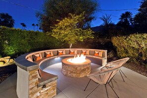 A circular outdoor seating area with a fire pit, stone walls, and a cushioned bench. - "La Veranda" a Movie Colony Palm Springs Resort Pool and View Home, #069334 (Palm Springs)