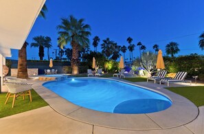 A swimming pool with lounge chairs and umbrellas, surrounded by palm trees and a well-maintained lawn. - "La Veranda" a Movie Colony Palm Springs Resort Pool and View Home, #069334 (Palm Springs)