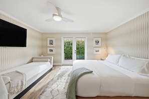A hotel room with a bed, a smaller bed, a television, a ceiling fan, and a view through the door. - "La Veranda" a Movie Colony Palm Springs Resort Pool and View Home, #069334 (Palm Springs)