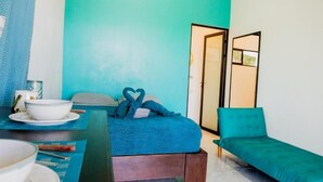 Una habitación con una cama, un sofá y una zona de comedor con mesa y sillas.