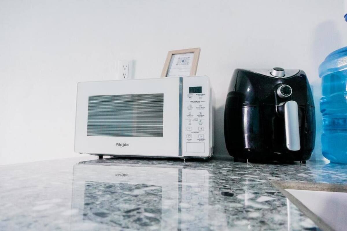 Una cocina con un microondas blanco, una cafetera negra y un dispensador de agua grande en la encimera.