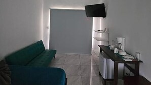 Una habitación pequeña y moderna con una cama, un escritorio, una silla y un televisor montado en la pared.