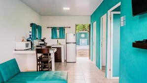 Una cocina compacta equipada con microondas, refrigerador y un comedor con un sofá y mesa color turquesa.
