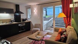 A modern kitchen with a dining area, a sofa, and a view of the outside. - Picasso | Terrace & Garden | Honfleur City Center (Honfleur)