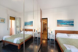 A hotel room with two beds, a large mirror, and artwork depicting ocean scenes. - Casa Aladino By Arenzanohost (Arenzano)