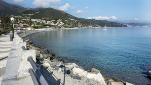 A coastal promenade with a stone railing, clear blue water, and a town in the background. - Casa Azzurra - One Bedroom Apartment, Sleeps 4 (Arenzano)
