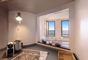 Une chambre moderne équipée d’une cuisinière à gaz, d’une machine à café et d’une grande fenêtre donnant sur la mer.
