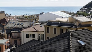 Uma vila costeira com telhados de terracota, vista para o mar e uma mistura de edifícios residenciais.