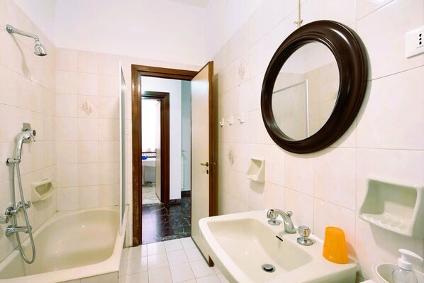 Une salle de bain avec deux lavabos, une douche, un miroir et une porte donnant sur une autre pièce.