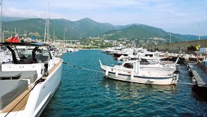 Een jachthaven met aangemeerde boten, een heldere lucht en bergen op de achtergrond.