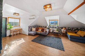 A loft-style room with a dining area, a sofa, a small table, and a window with a view.