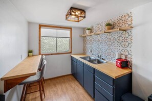 A compact kitchen with a wooden countertop, a sink, and a window.