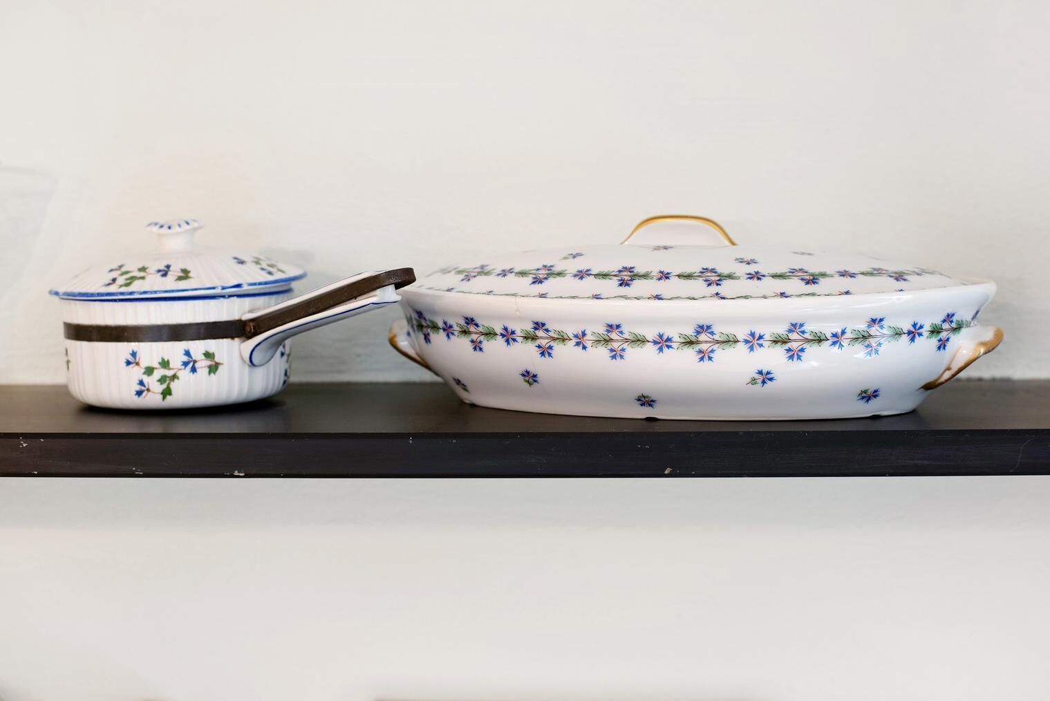 Un pot en céramique blanche orné d’un motif floral et doté d’un couvercle, posé sur une surface sombre.