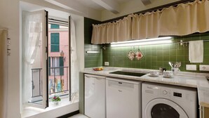 A compact kitchen with a dishwasher, washing machine, and a window with a view of a building. - Casa Fiordaliso - One Bedroom Apartment, Sleeps 4 (Arenzano)