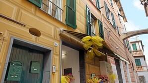 A yellow building with green shutters, a door, and a window. - Casa Fiordaliso - One Bedroom Apartment, Sleeps 4 (Arenzano)