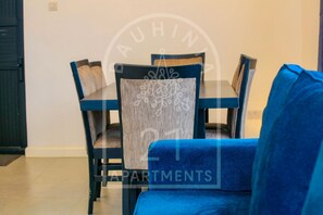 Uma área de refeições com um sofá azul, uma mesa e cadeiras.