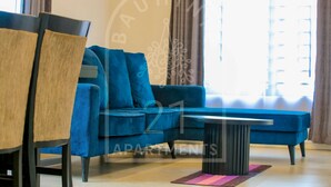 Un soggiorno moderno con un divano blu, un tavolino rotondo e una sedia in legno.