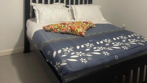 Un letto singolo con una testiera scura, cuscini bianchi e una coperta a fiori blu.