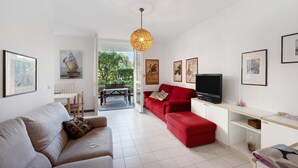 Ein modernes Wohnzimmer mit einer grauen Couch, einer roten Couch, einem Fernseher und Kunstwerken an den Wänden.