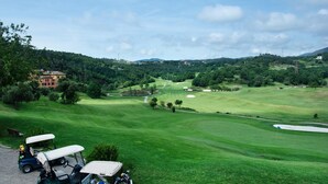 A golf course with a clubhouse, a pond, and a hilly landscape. - Casa Luxury Golf - One Bedroom Apartment, Sleeps 3 (Arenzano)