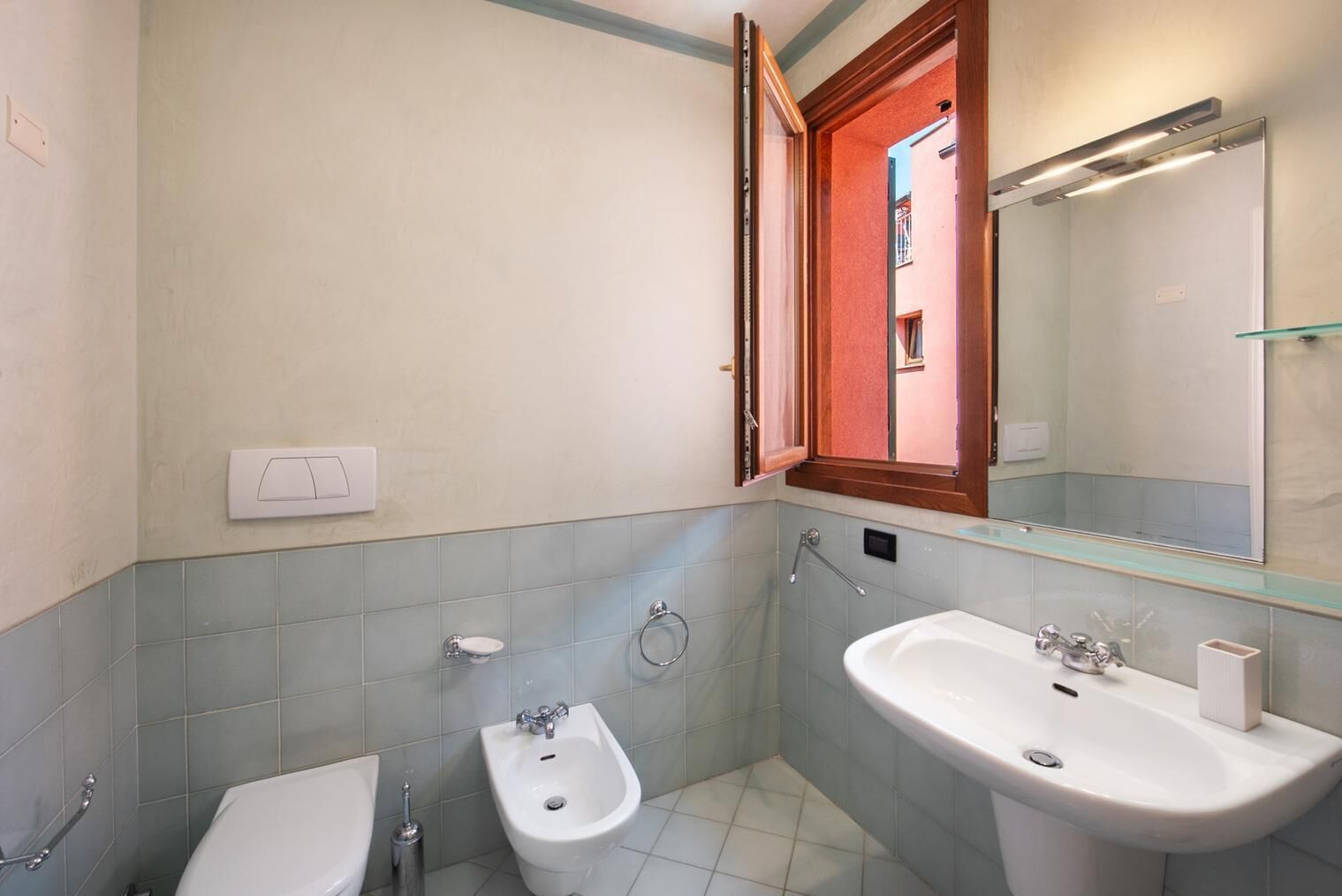 A bathroom with a toilet, bidet, and two sinks.