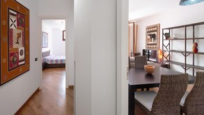A modern living space with a dining area, a sofa, and a bookshelf. - Casa Luxury Golf - One Bedroom Apartment, Sleeps 3 (Arenzano)