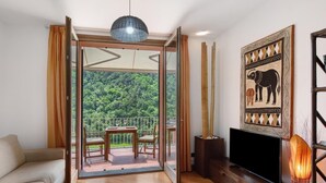 A room with a balcony, a sofa, a table with chairs, a television, and a decorative wall piece. - Casa Luxury Golf - One Bedroom Apartment, Sleeps 3 (Arenzano)
