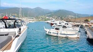 Una marina con barche ormeggiate, cielo sereno e montagne sullo sfondo.