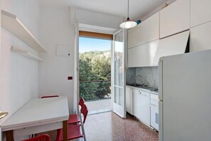 Una cocina compacta con armarios blancos, un lavamanos y una zona de comedor con una mesa y sillas.