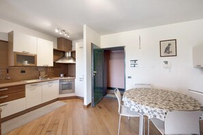 A compact kitchen with modern appliances, a dining area with a table and chairs, and a small dining table with a patterned tablecloth. - Casa Pasqua - One Bedroom Apartment, Sleeps 3 (Arenzano)