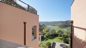 Vista da un balcone su un campo da golf, con cielo sereno.