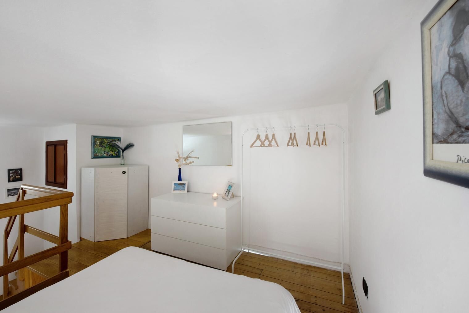 Ein Schlafzimmer mit Bett, Kommode, Schreibtisch und Spiegel.