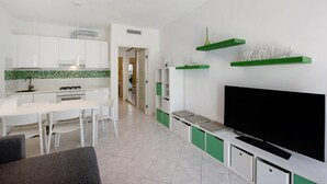 Et moderne køkken med hvide skabe, en grøn backsplash og et spiseområde med hvide stole og et bord.