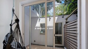Et moderne værelse med en skydedør til en balkon, en hængestol og udsigt udad.