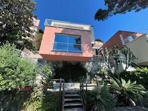 A modern building with a pink facade, a large window, and a balcony. - L'Ile d'Azur - Three Bedroom Villa, Sleeps 6 (Arenzano)