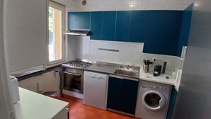 Uma cozinha compacta com fogão, forno, lava-louças e máquina de lavar.