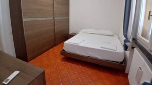 Quarto pequeno com cama, guarda-roupa e janela.