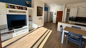 A modern kitchen with white cabinets, a built-in oven, and a dining area with a wooden table and chairs. - Casa Mimose - Two Bedroom Apartment, Sleeps 5 (Cogoleto)