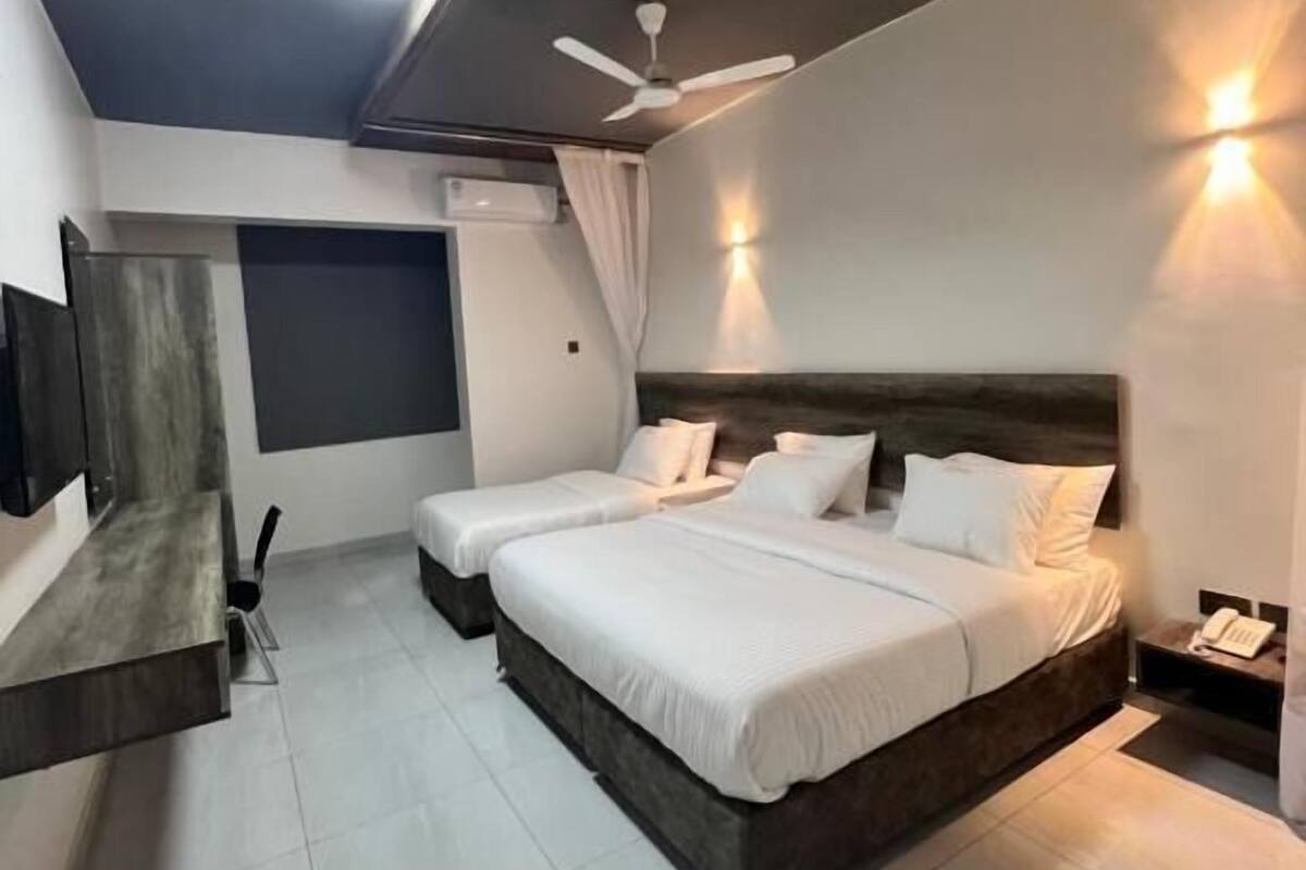 Un dormitorio moderno con dos camas, ventilador de techo, iluminación empotrada y un banco integrado.