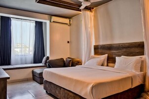 Un dormitorio con una cama grande, un asiento junto a la ventana y un ventilador de techo.